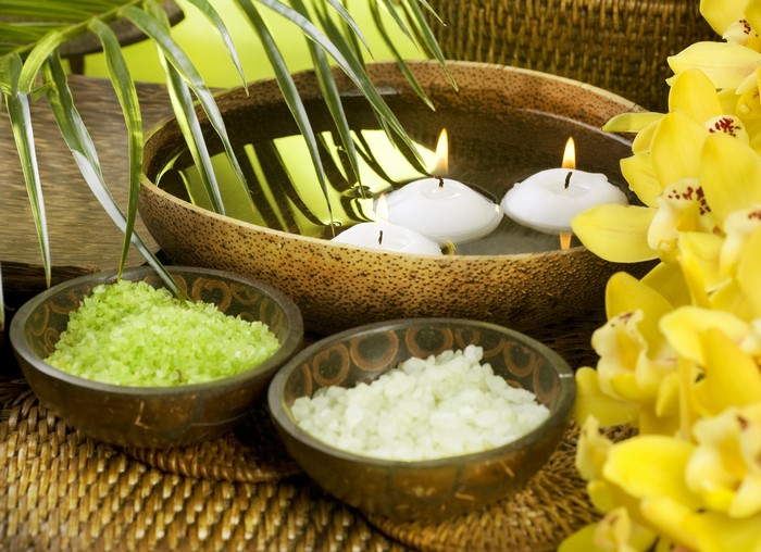 Spa setting with candles, orchids, and bath salts