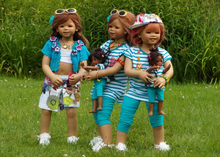 Three dolls in summer outfits in a park