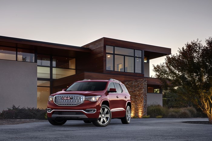 Red GMC Acadia All Terrain SUV parked in front of modern house