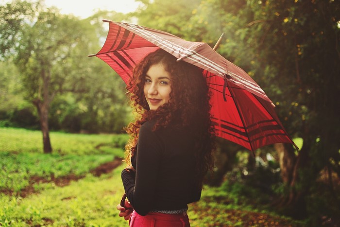 Woman with curly hair holding a red umbrella