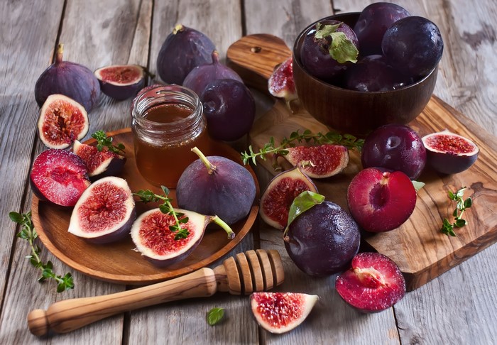 Fresh figs and plums with honey on a wooden table