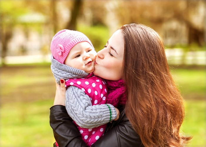 Mother kissing her baby in a park
