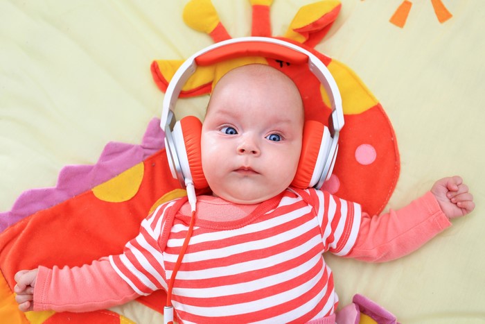 Baby wearing headphones on a giraffe toy
