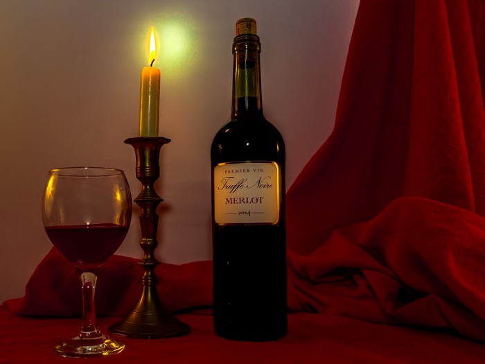 Bottle of Merlot wine with candle and glass