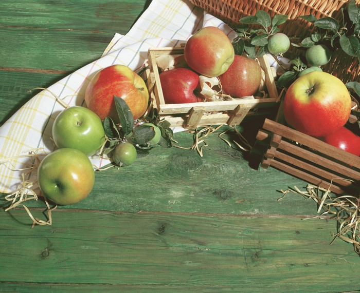 Apples in wooden crates on a green wooden surface