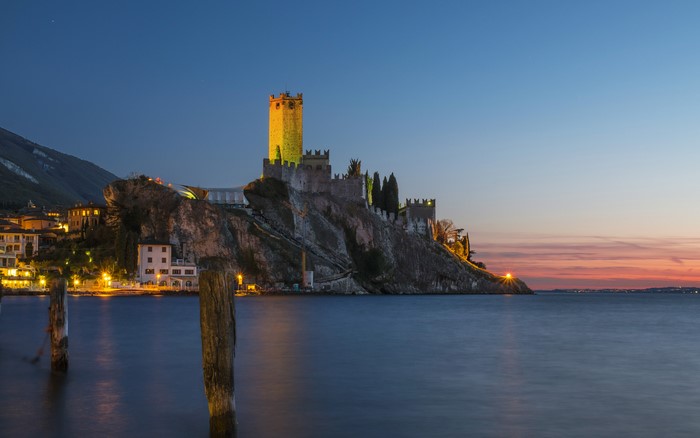 Castle on a rocky crag overlooking a lake at dusk
