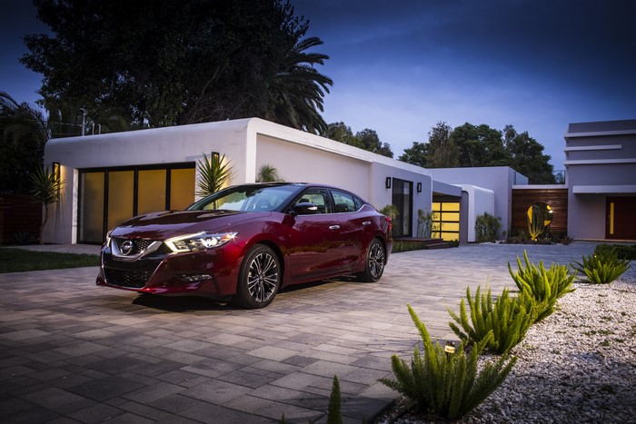 Red Nissan Maxima parked in front of a modern house