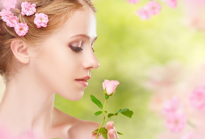Blonde girl with roses in hair smelling a rose