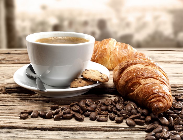 Coffee cup with croissants and coffee beans