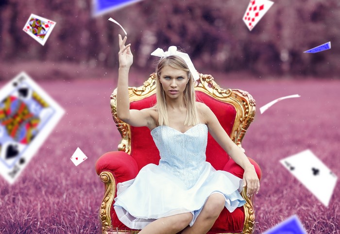 Woman in Alice costume sitting on armchair with cards