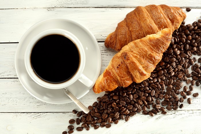 Coffee cup with croissants and coffee beans