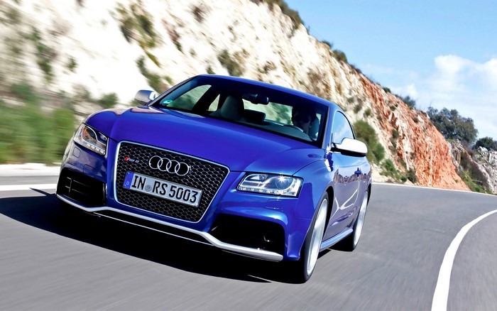 Blue Audi RS 5 driving on a winding road