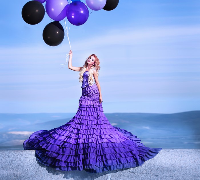 Blonde girl in purple dress holding balloons