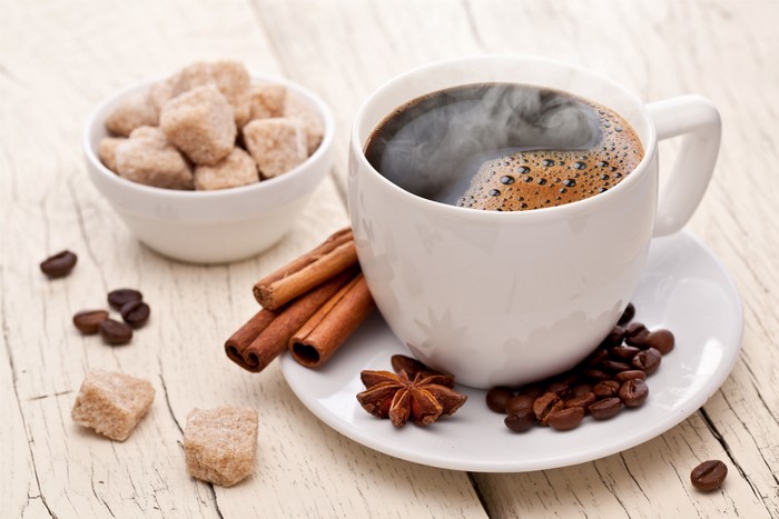 Coffee cup with cinnamon sticks and sugar cubes