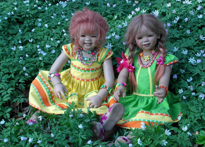 Two dolls sitting in a field of flowers