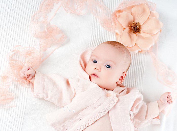 Baby in pink jacket with lace and flower