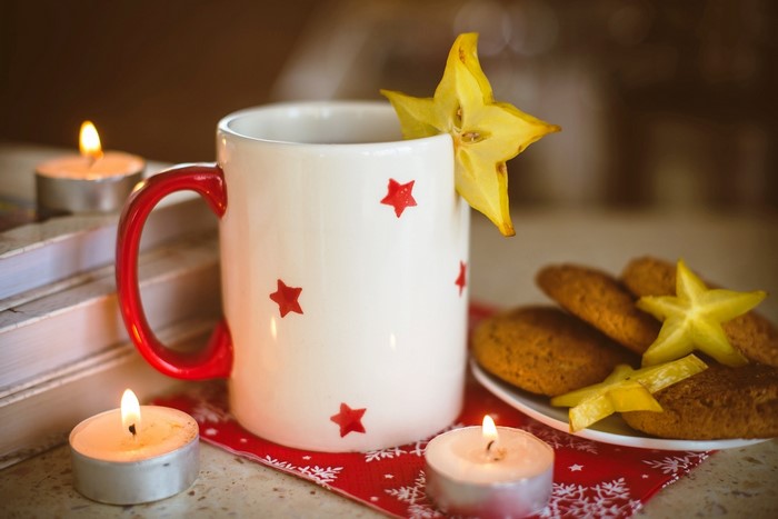 Mug with star fruit and cookies by candlelight