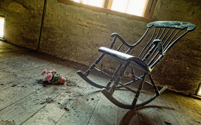 Old rocking chair and flowers in an abandoned room