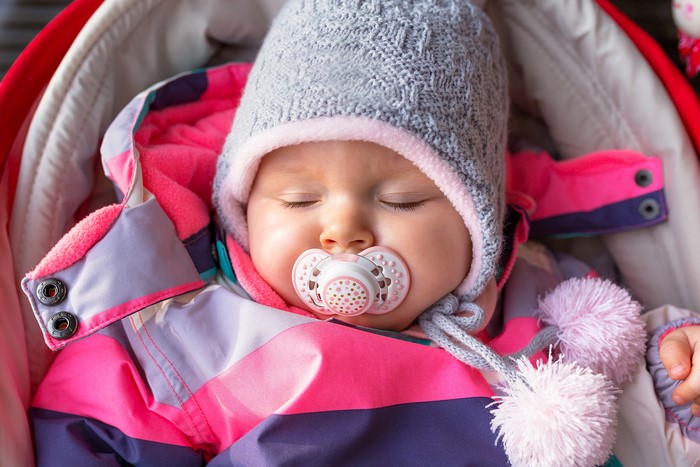 Baby sleeping with pacifier in winter clothes