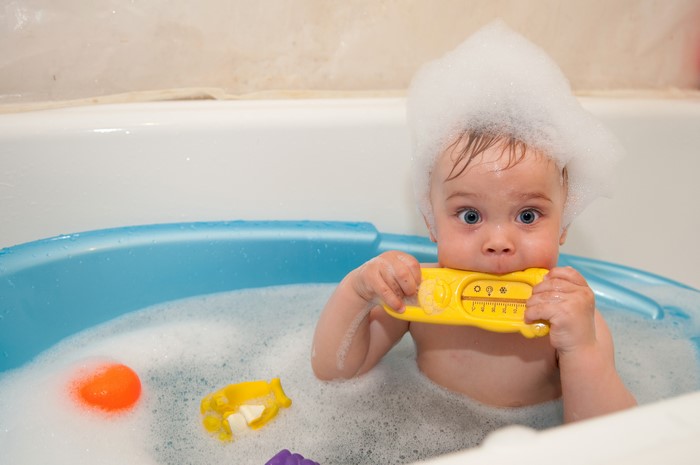 Baby playing with toys in a bathtub with foam