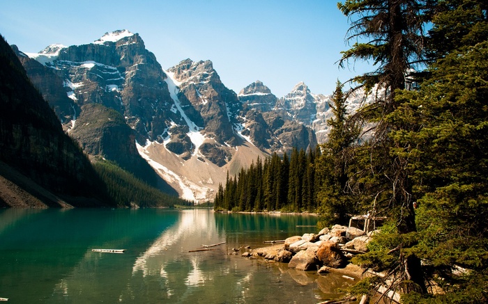 Turquoise lake with snow-capped mountains and pine trees