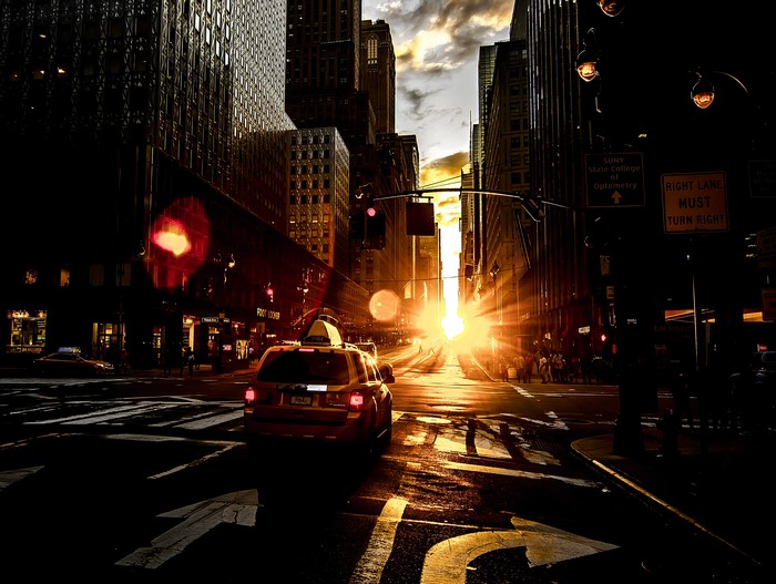 Yellow taxi on a city street at sunset