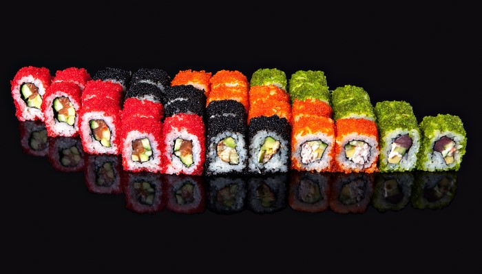 Assortment of colorful sushi rolls on a black background