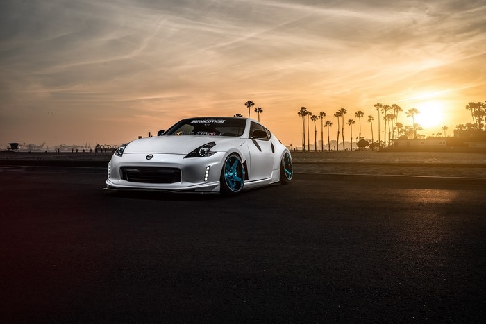 White Nissan 370Z Avant with blue rims at sunset