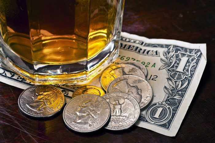 Whiskey glass with dollar bill and coins