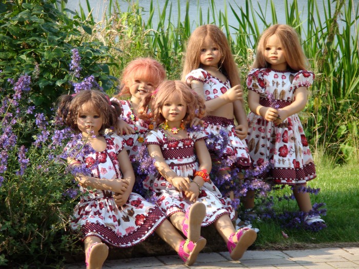 Five dolls in floral dresses in a park