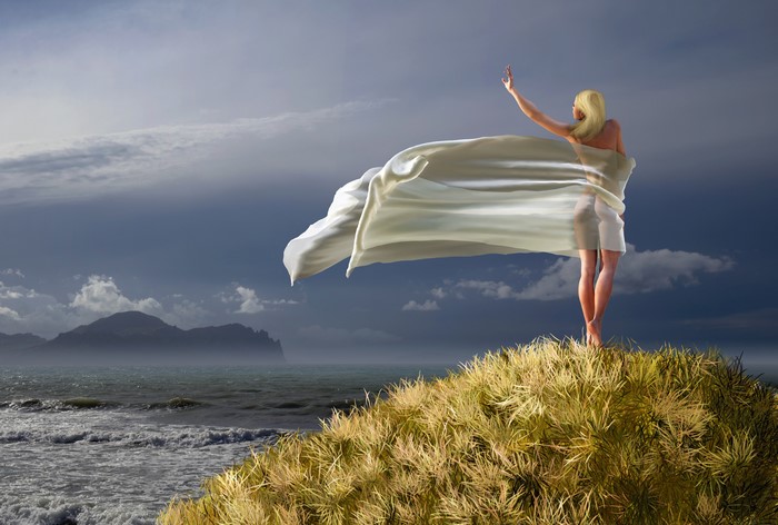 Blonde girl on a grassy hill by the sea