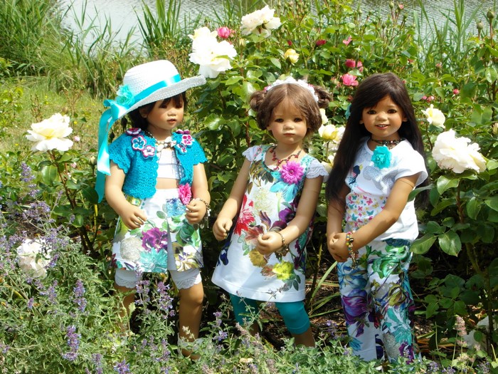 Three dolls in a garden with roses
