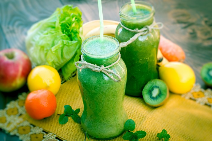 Two jars of green smoothie with fruits and vegetables