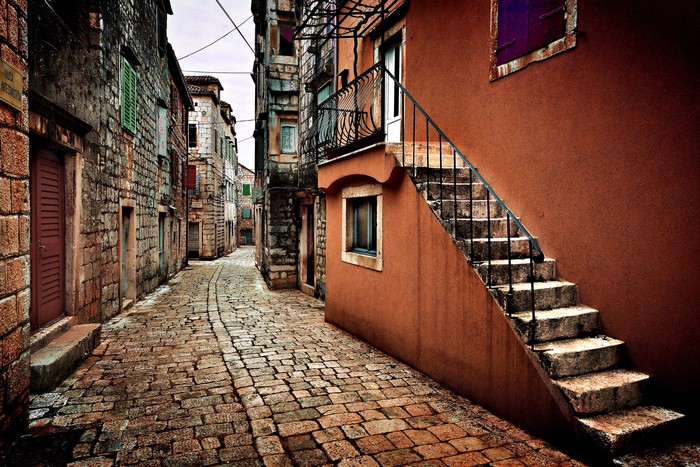 Cobblestone alley with stone houses and outdoor stairs in Stari Grad, Croatia