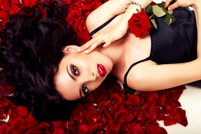 Woman with dark hair lying on rose petals