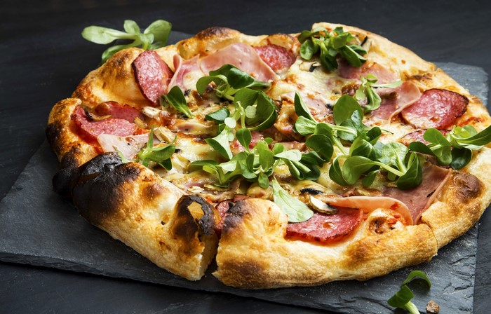 Pizza with sausage, ham, and greens