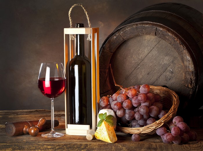 Wine bottle, glass, grapes, cheese, and barrel