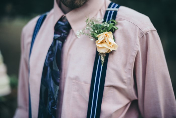 Man wearing pink shirt, tie, and suspenders with boutonniere