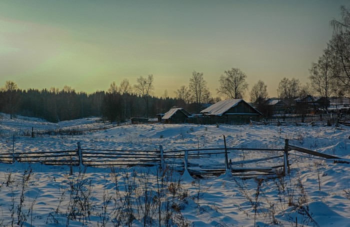 Winter village in Russia with snow-covered houses and fences