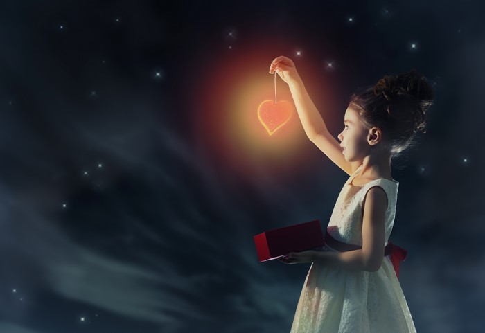 Girl holding a glowing heart lantern at night