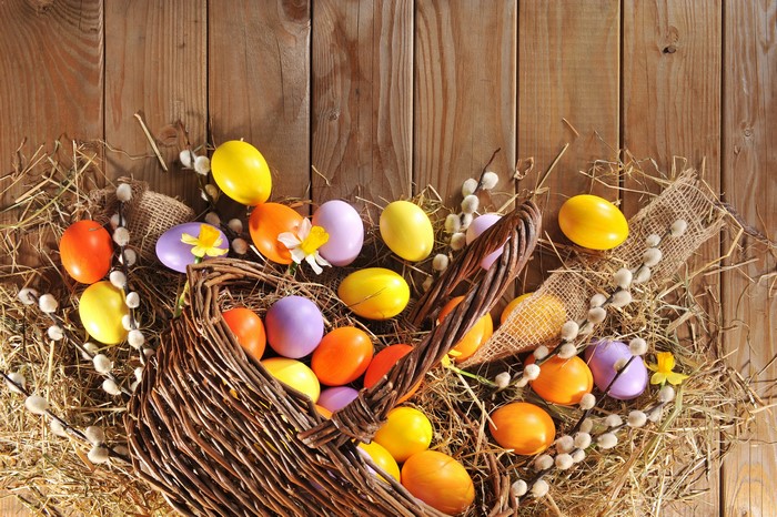 Easter eggs in a wicker basket on wooden background