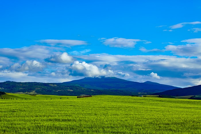 Green fields and mountains under a blue sky in Tuscany
