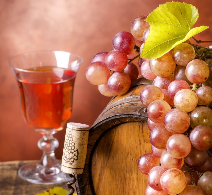 Wine glass, grapes, and barrel with corkscrew
