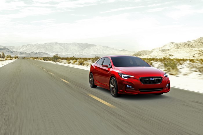 Red Subaru Impreza Concept Sedan driving on a desert road