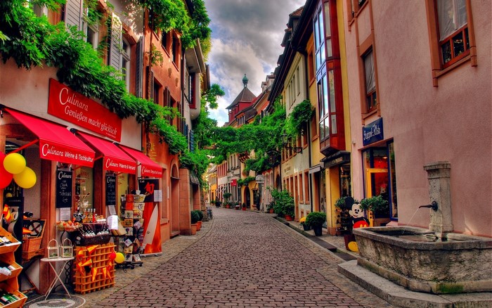 Cobblestone street with shops and fountain