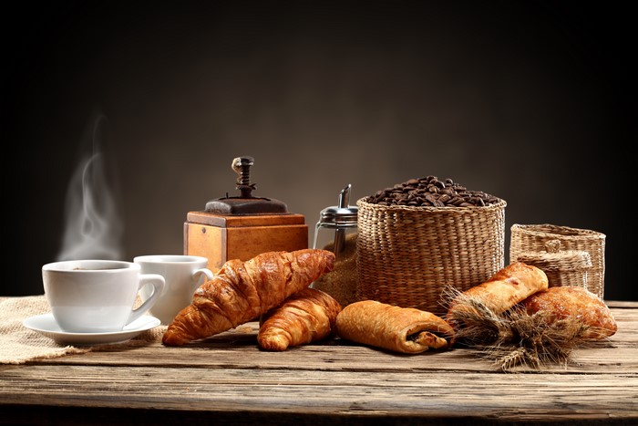 Coffee cups, croissants, and coffee beans on a wooden table