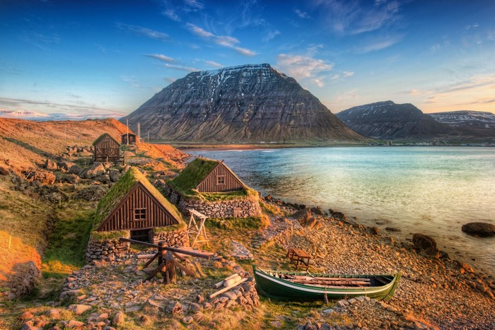 Traditional Icelandic turf houses by a fjord with mountains