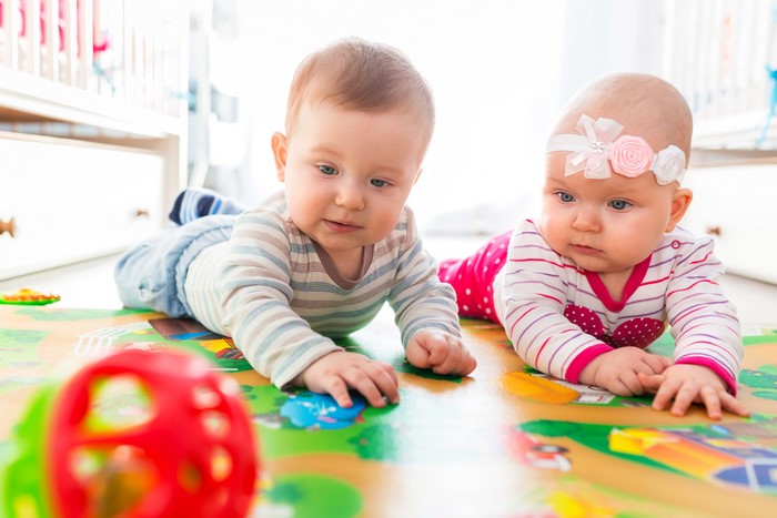 Two Infants Playing on a Mat