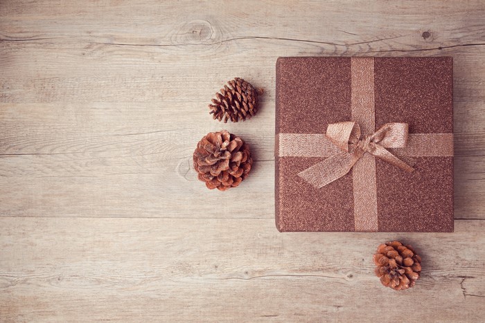Gift box with pine cones on wooden background