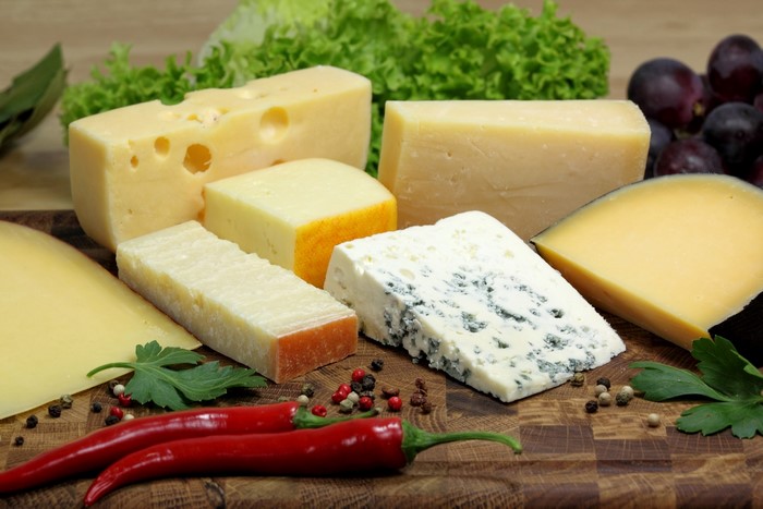 Assortment of cheeses with chili peppers and grapes